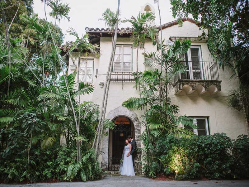 couple holding hands in front of house